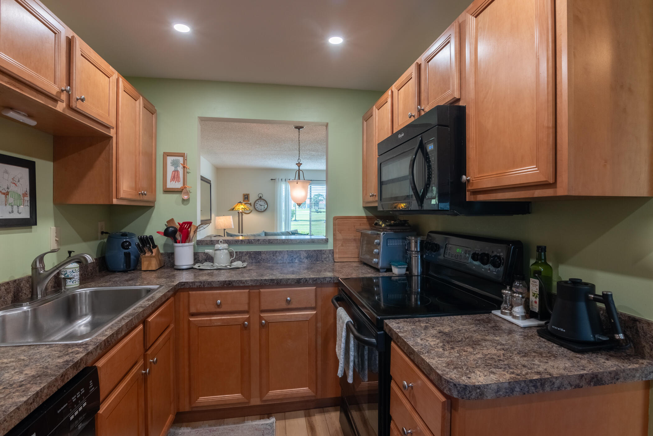 5403 Southeast Miles Grant Road, Unit 111 Stuart, FL 34997 - Photo 5 of 29 a kitchen with granite countertop a sink a stove and a wooden cabinets