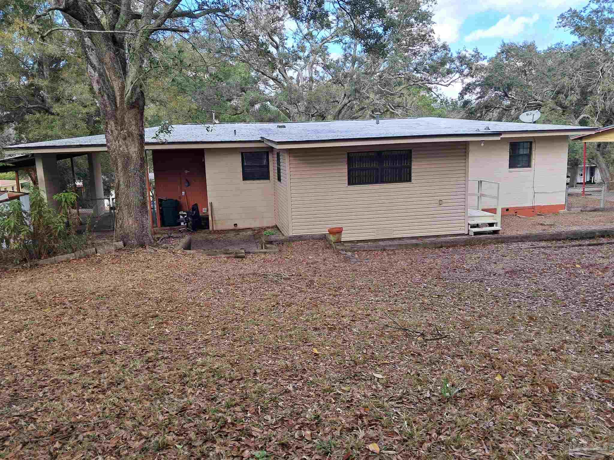 4929 Springhill Drive Pensacola, FL 32503 - Photo 14 of 16 a backyard of a house with large trees and brick wall