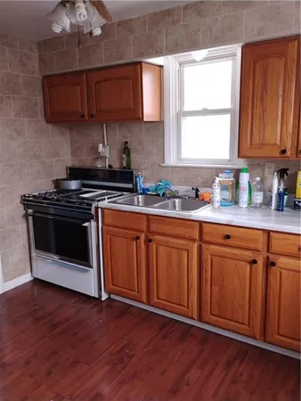 a kitchen with stainless steel appliances granite countertop wooden floors a stove a sink and a window
