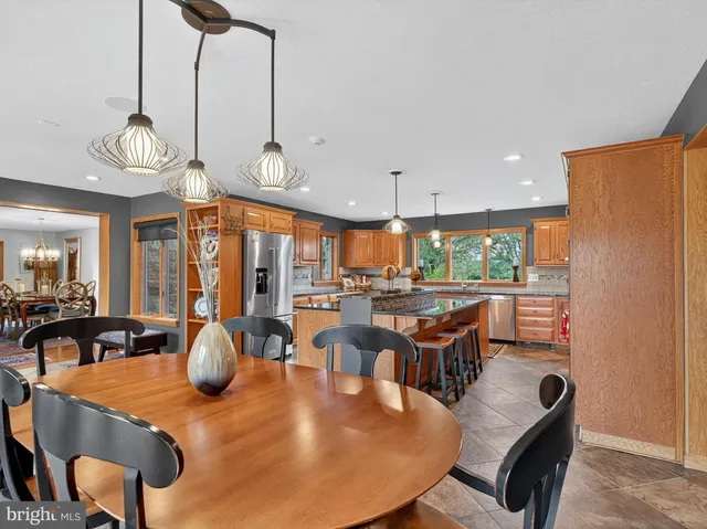 a dining room with stainless steel appliances a dining table and chairs with wooden floor