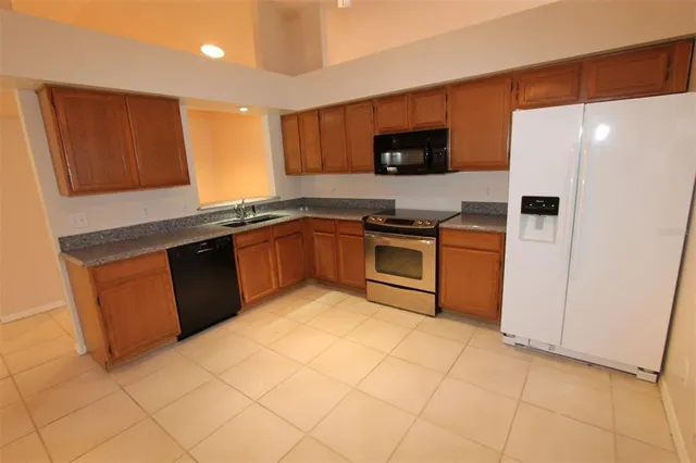 a kitchen with stainless steel appliances granite countertop a stove a sink and a refrigerator