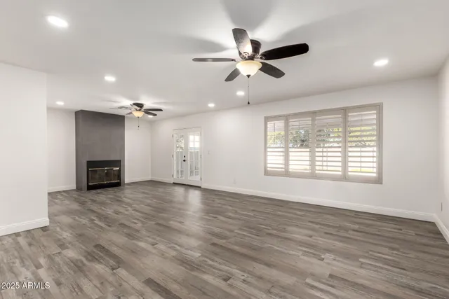 a view of an empty room with a window and wooden floor