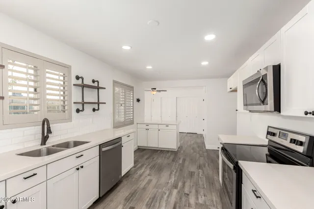 a kitchen with a sink dishwasher stove and white cabinets with wooden floor