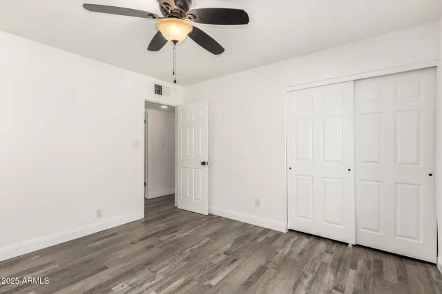 a view of a room with a chandelier fan and wooden floor