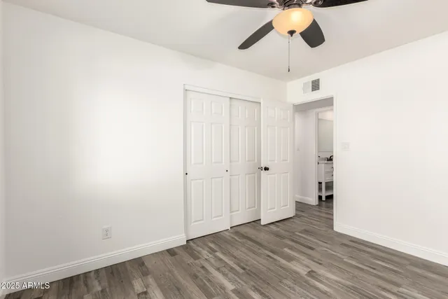 an empty room with wooden floor and ceiling fan