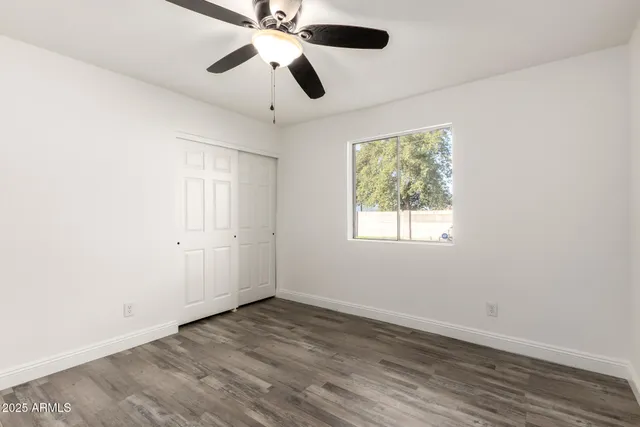 an empty room with wooden floor and ceiling fan