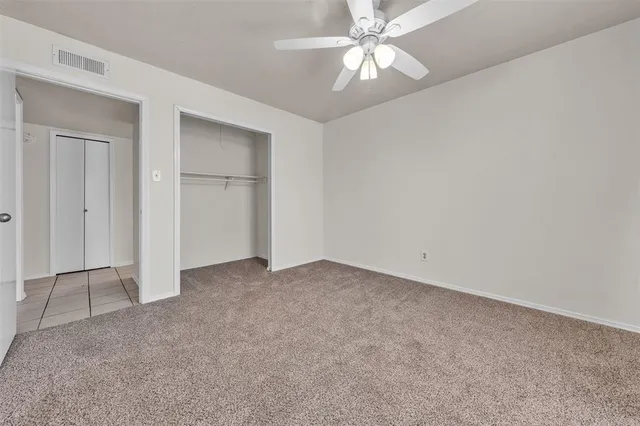 an empty room with a ceiling fan and a window
