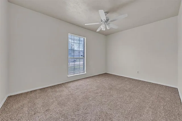 en empty room with windows and chandelier fan