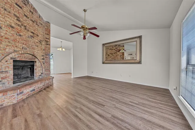 an empty room with windows fireplace and wooden floor