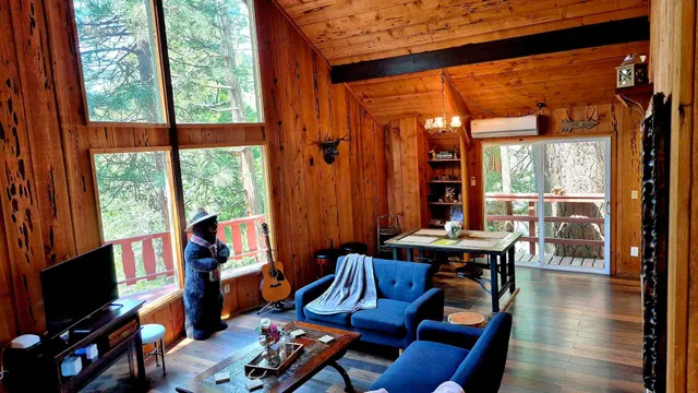 a living room with furniture a flat screen tv and floor to ceiling window