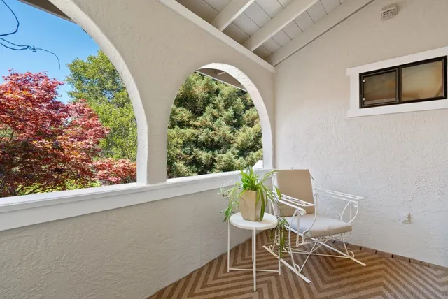 a view of a house with potted plants and a bench