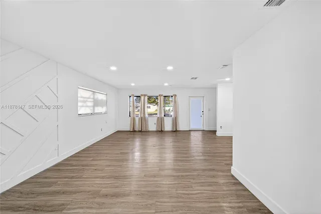a view of empty room with wooden floor and window
