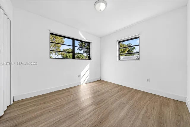 an empty room with wooden floor and windows