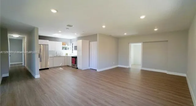 a view of an empty room with wooden floor and closet area