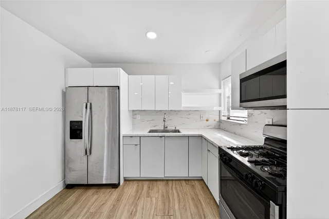 a kitchen with stainless steel appliances a sink dishwasher a refrigerator and a stove top oven