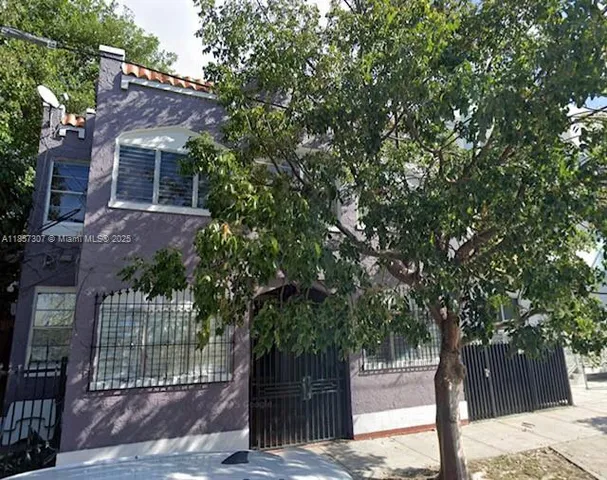 a front view of a house with a tree