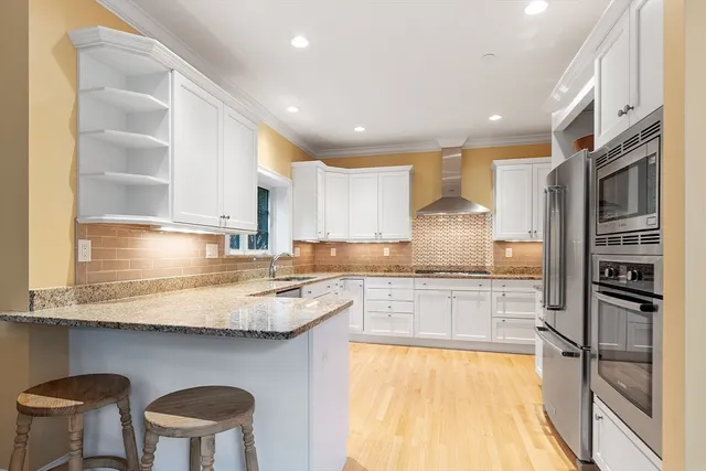 a kitchen with stainless steel appliances granite countertop a sink a stove a refrigerator cabinets and chairs