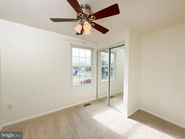 an empty room with windows and fan