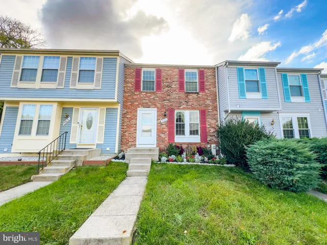 a view of a brick building next to a yard with big trees