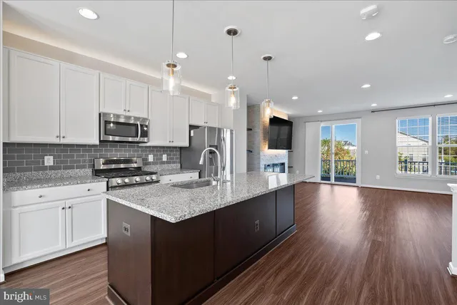 a kitchen with stainless steel appliances granite countertop a sink dishwasher a stove and a oven with wooden floor