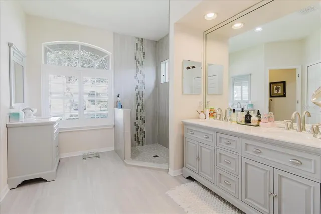 a spacious bathroom with double vanity a sink a mirror a shower and a bathtub