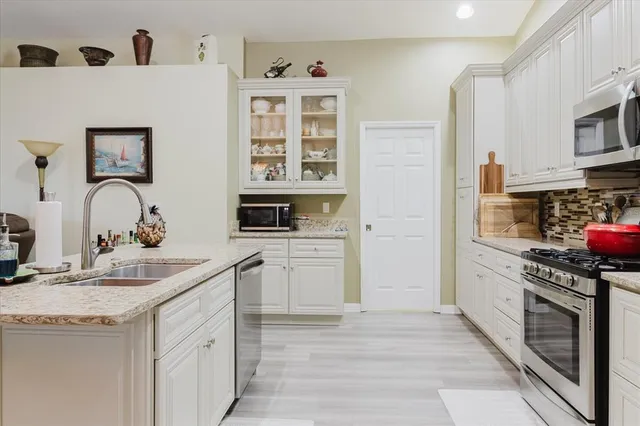 a kitchen with stainless steel appliances granite countertop a sink stove and refrigerator