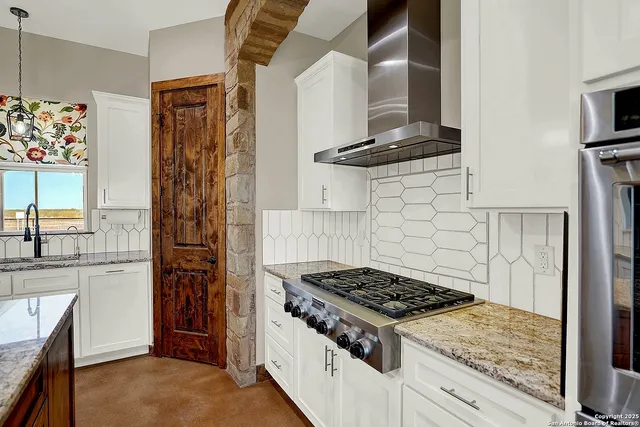 a kitchen with stainless steel appliances granite countertop a refrigerator a sink dishwasher a stove and white cabinets with wooden floor