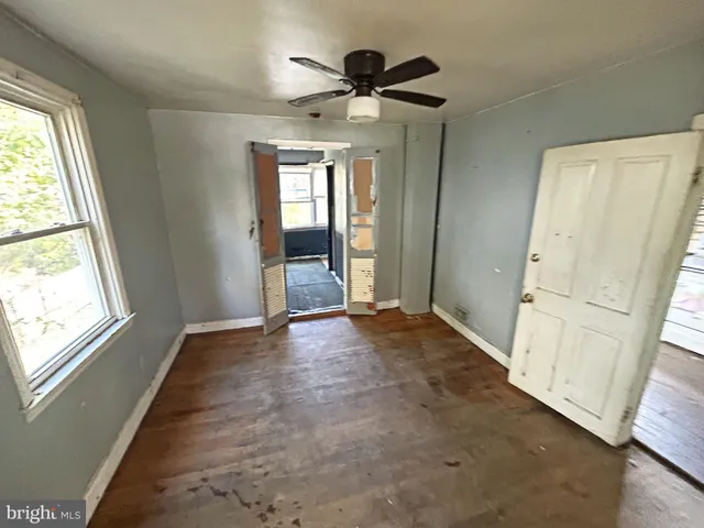 a view of empty room with wooden floor and fan