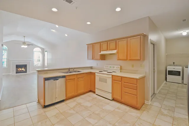 a large kitchen with granite countertop a sink and white cabinets