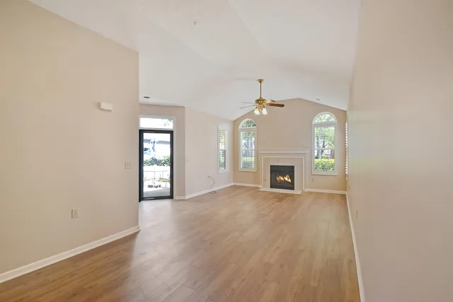 an empty room with wooden floor fireplace and windows