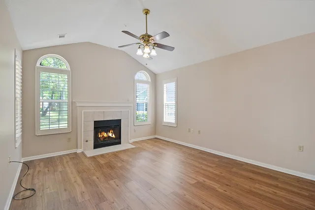 an empty room with windows fireplace and wooden floor