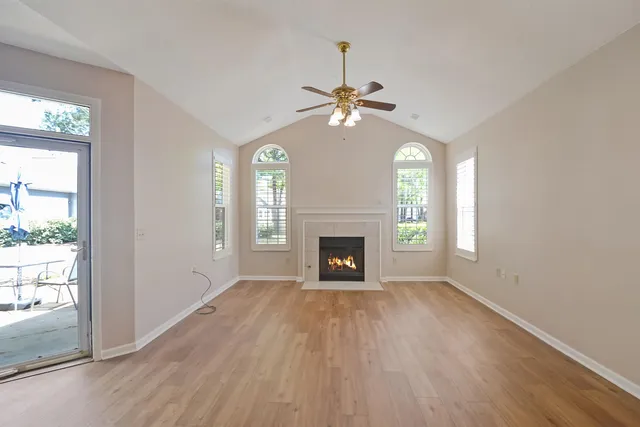 an empty room with windows fireplace and wooden floor