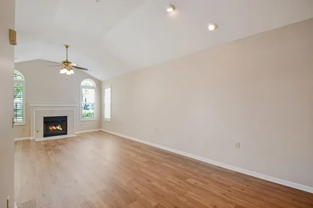 a view of an empty room with wooden floor fireplace and a window