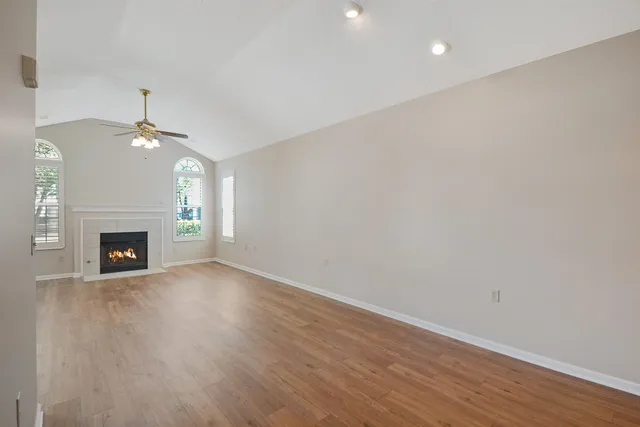 a view of an empty room with wooden floor fireplace and a window