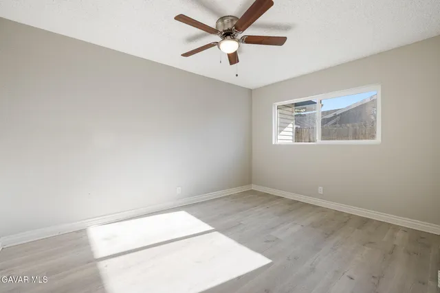 an empty room with ceiling fan and window