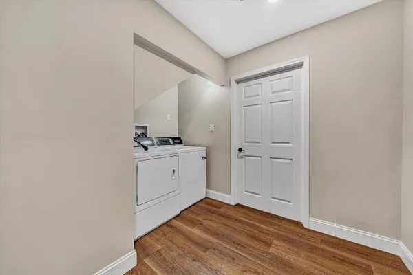 a view of an empty room with wooden floor and a ceiling fan
