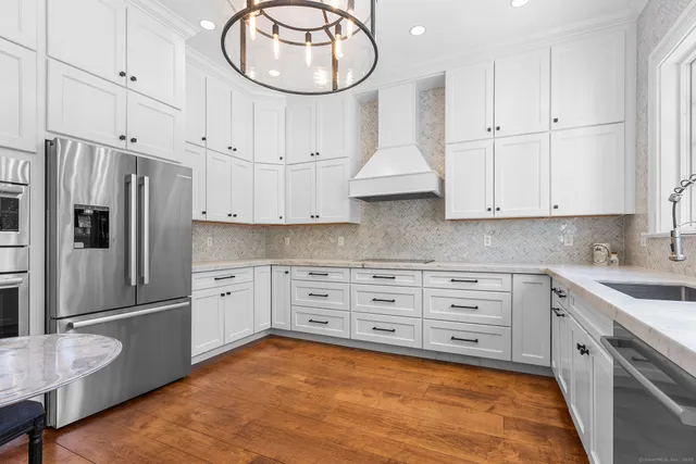 a kitchen with kitchen island granite countertop lots of white stainless steel appliances cabinets and a sink