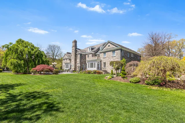 a view of a house with a big yard plants and large trees