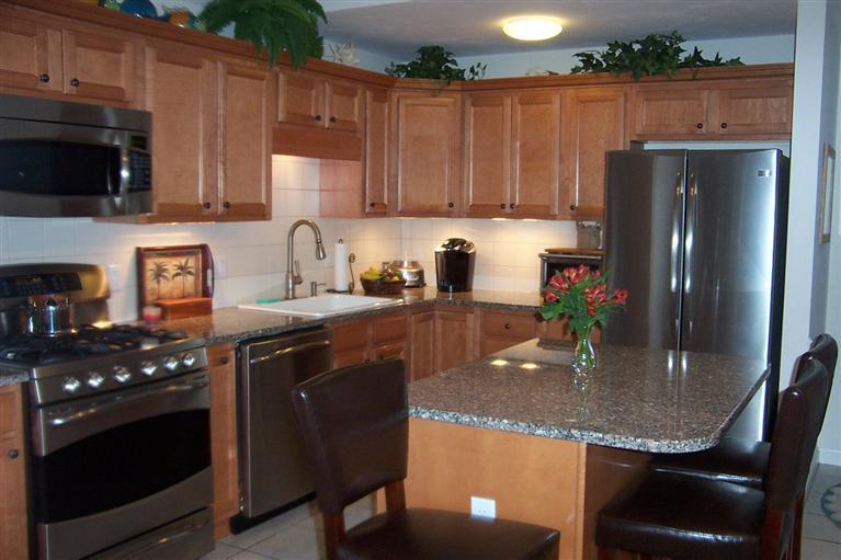 16 Gold Leaf Lane, Unit 16 Mashpee, MA 02649 - Photo 9 of 29 a kitchen with granite countertop kitchen island stainless steel appliances a sink a stove a refrigerator a microwave a sink and cabinets