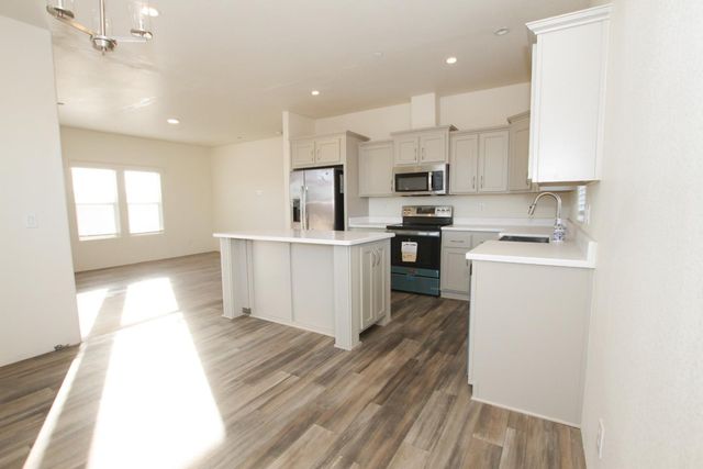 a kitchen with stainless steel appliances a sink a stove a refrigerator cabinets and a window