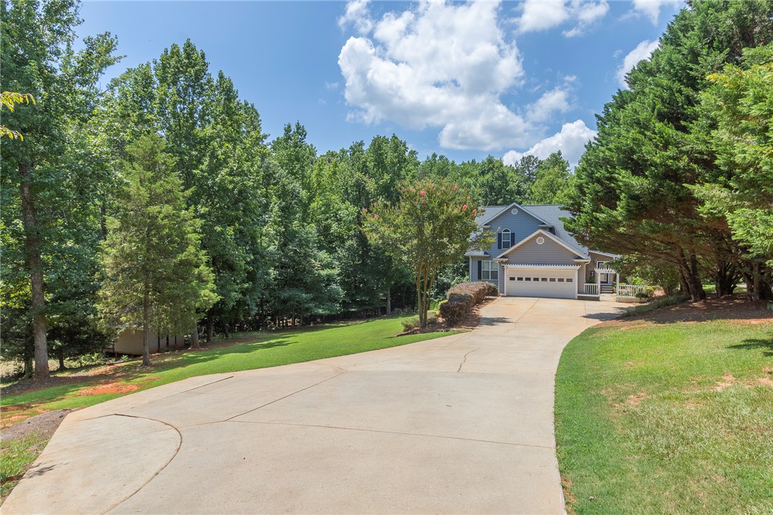 125 Inlet Pointe Drive Anderson, SC 29625 - Photo 7 of 39 A long paved driveway leads to a welcoming two-story home, nestled among verdant trees and lush landscaping.