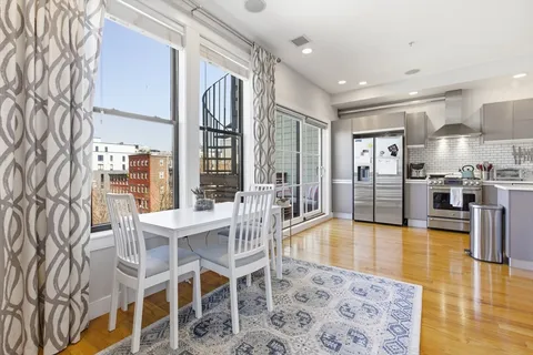 a dining room with stainless steel appliances furniture large window and wooden floor