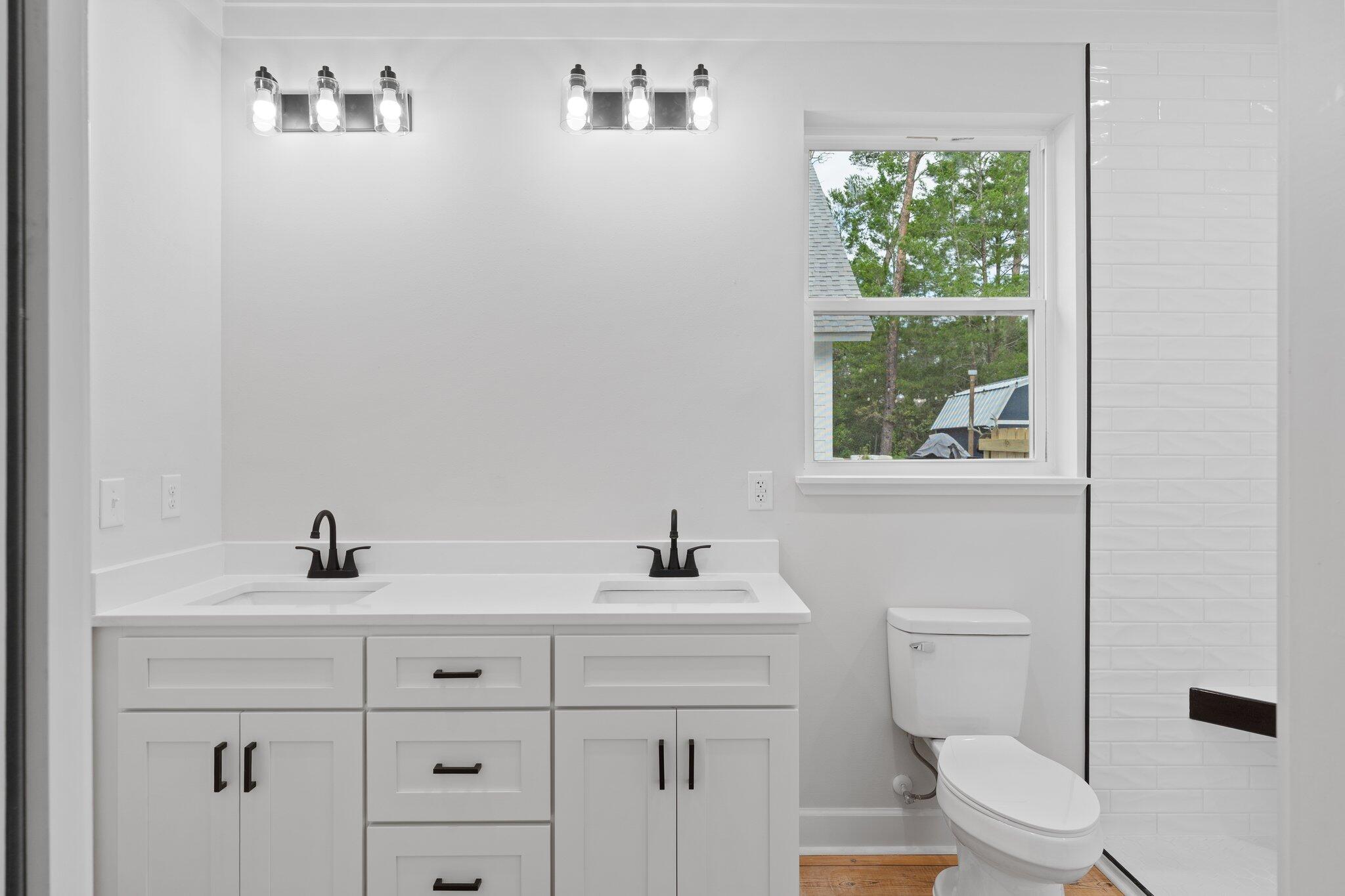 45 Laurel Oak Lane Santa Rosa Beach, FL 32459 - Photo 26 of 30 a bathroom with a toilet a sink a window and mirror