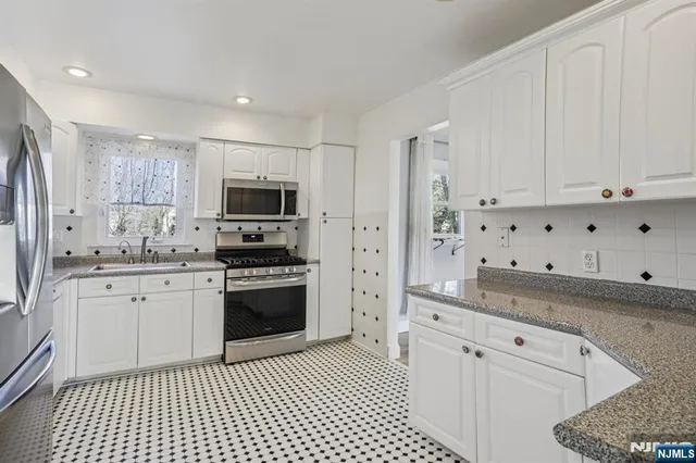 a kitchen with granite countertop white cabinets and stainless steel appliances