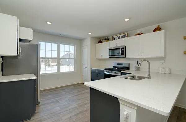 a kitchen with a sink a stove a refrigerator and white cabinets