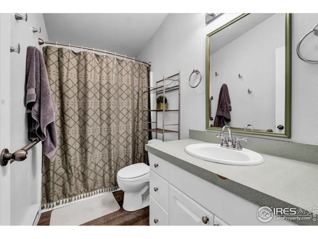 a bathroom with a sink a toilet a mirror and shower curtain