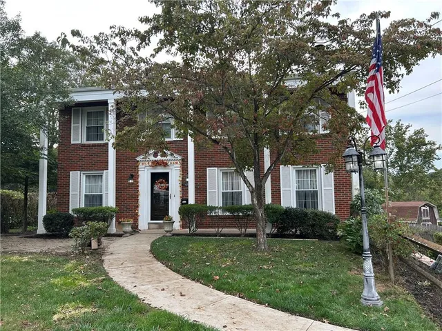 a front view of a house with a yard and trees