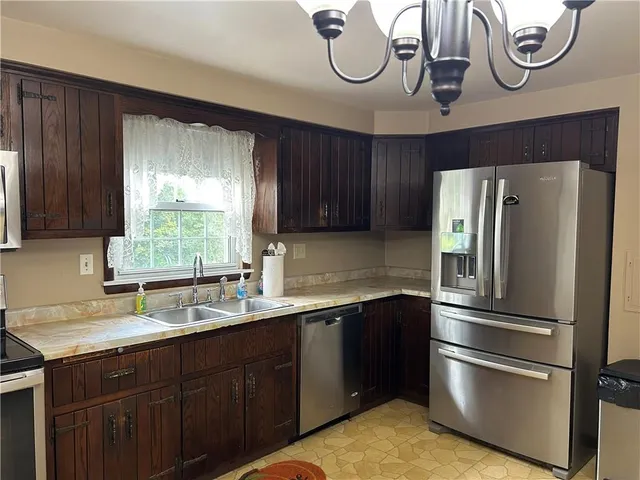 a kitchen with stainless steel appliances granite countertop a sink a stove a refrigerator and cabinets