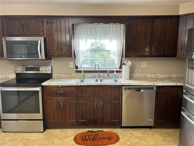 a kitchen with a sink and a stove with wooden cabinets