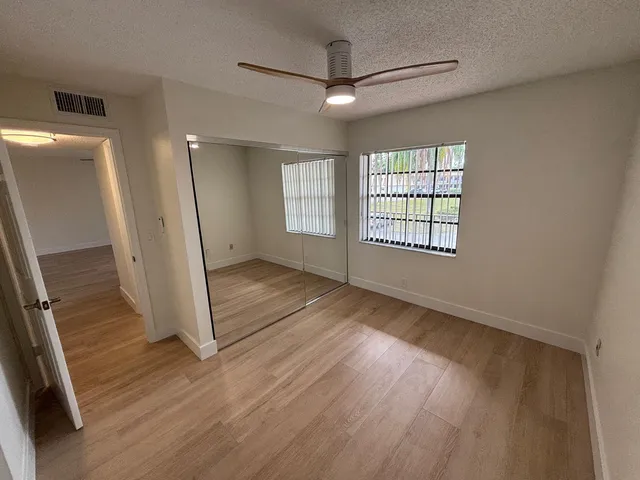 an empty room with wooden floor and a ceiling fan